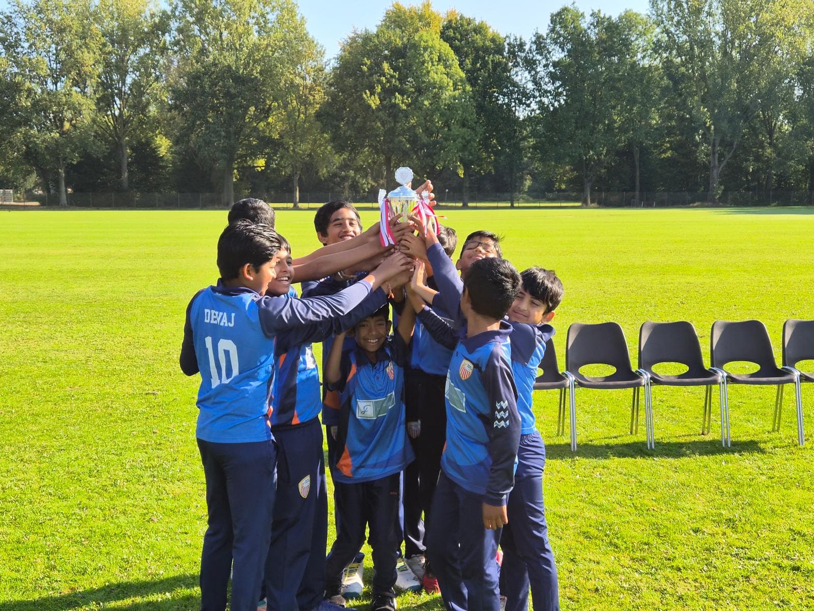 ECC youth players celebrating together as they lift a trophy